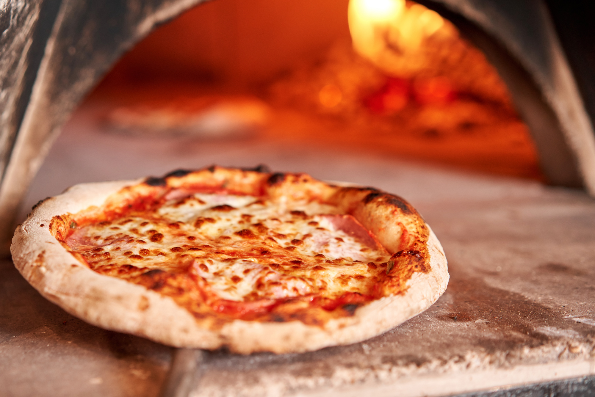 Baked tasty margherita pizza in Traditional wood oven in Naples restaurant, Italy. Original neapolitan pizza. Red hot coal