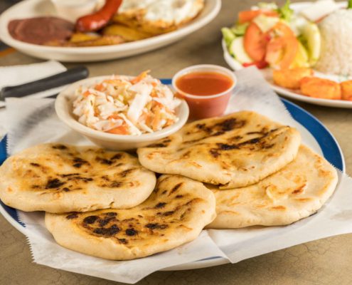 a dish of pupusas and others mexican food on the take out mexican restaurant table