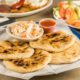 a dish of pupusas and others mexican food on the take out mexican restaurant table