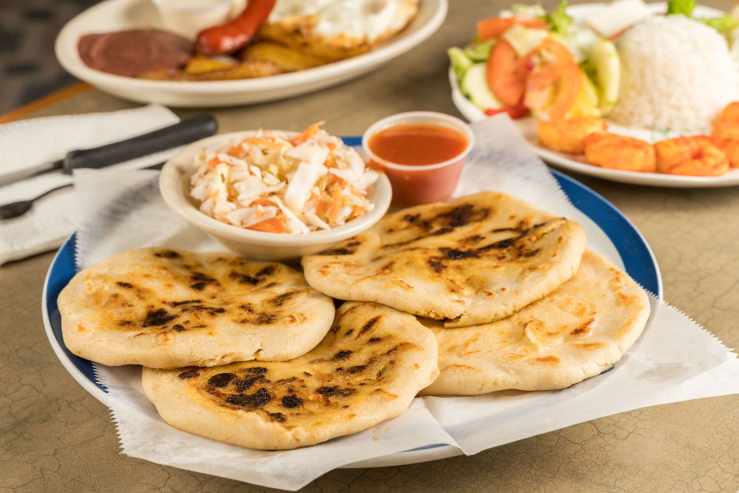 a dish of pupusas and others mexican food on the take out mexican restaurant table