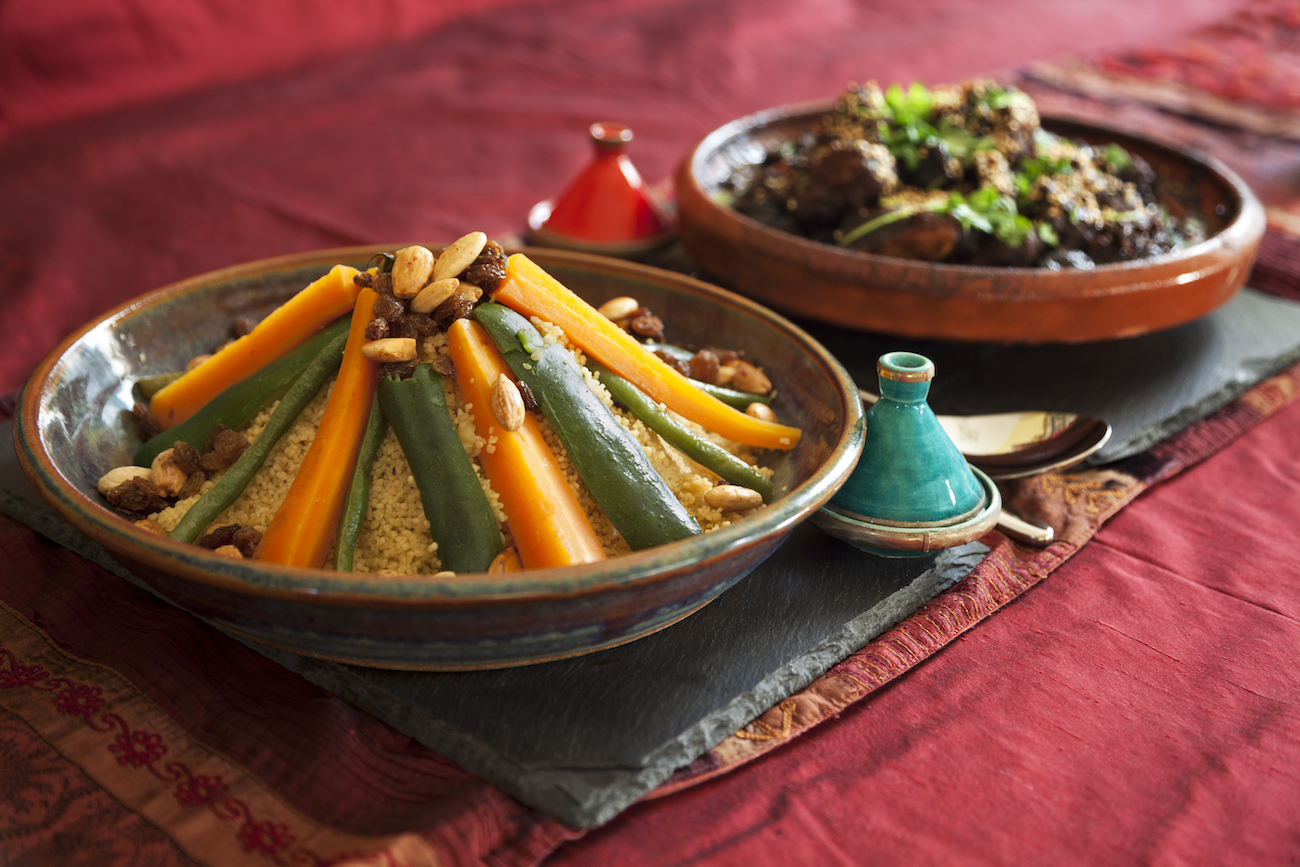 Vegetable couscous and Meat and prune tagine garnished with fresh coriander and sesame seeds. Authentic pepper and salt pots and table linen. North African Food