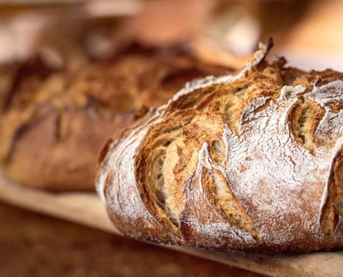 Round bread close-up. Freshly baked sourdough bread with a golden crust on bakery shelves. Baker shop context with delicious bread. Pastry items.
