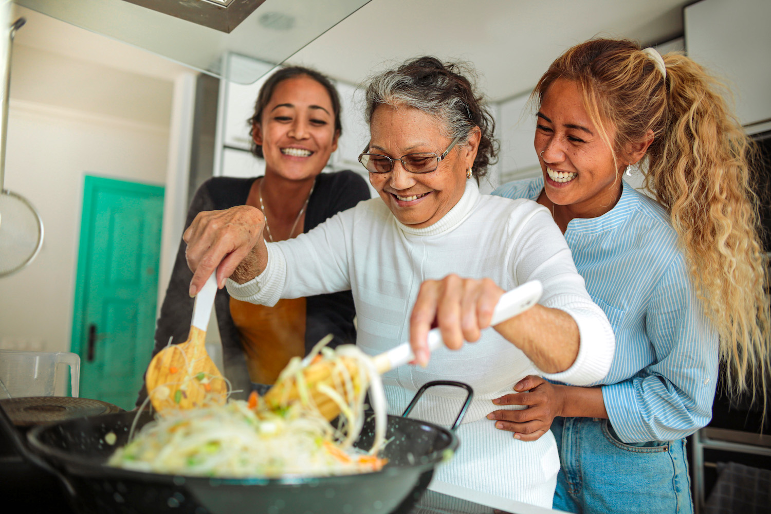 Filipino family cooking together at home - Granddaughters helping their grandmother to cook a traditional asian meal Cooking