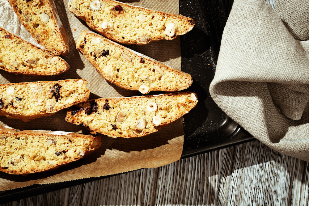 Italian biscotti cookies on black baking sheet. Fresh baked cookies with nuts and dried cranberries.