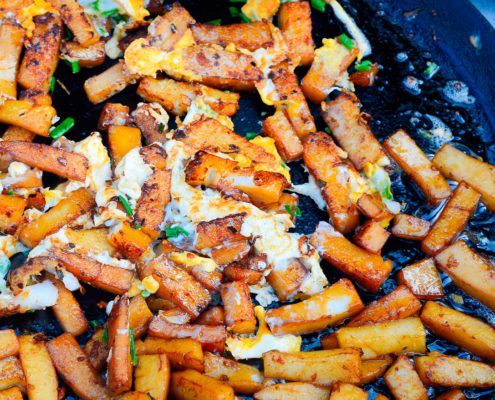 Vietnam street Food ( mon an duong pho ) Fried flour ( Bot Chien Trung ) with egg, oil and green onion in the black frying pan.
